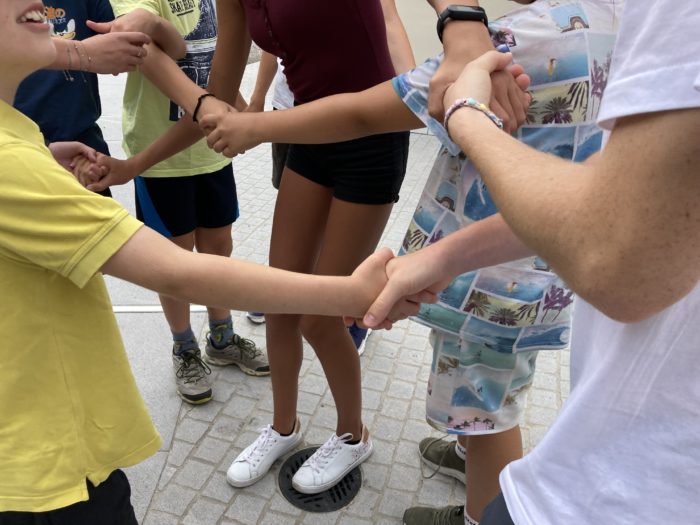 Eine Gruppe von Schüler*innen hält ihre Hände überkreuzt fest.
