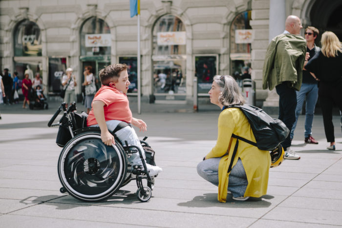 Ein Mann im Rollstuhl spricht mit einer Frau, die auf dem Boden kniet.