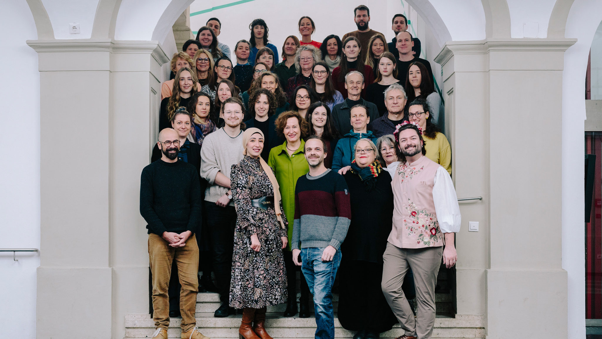 Ca. 43 Personen stehen auf den Stufen einer Stiege im Foyer des Graz Museums und blicken in die Kamera.